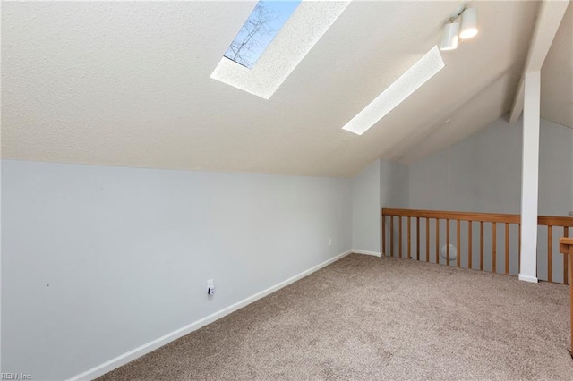 bonus room featuring a textured ceiling, carpet floors, lofted ceiling with skylight, and baseboards