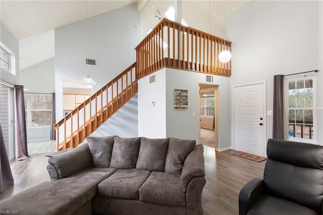 living room featuring stairs, high vaulted ceiling, wood finished floors, and visible vents