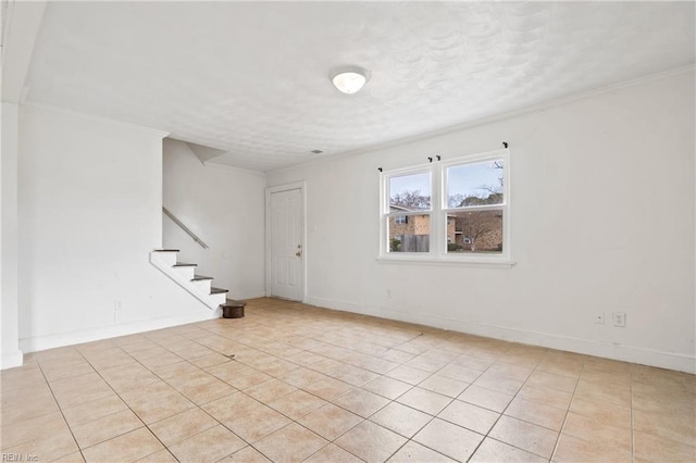 spare room featuring light tile patterned floors, baseboards, stairway, and crown molding