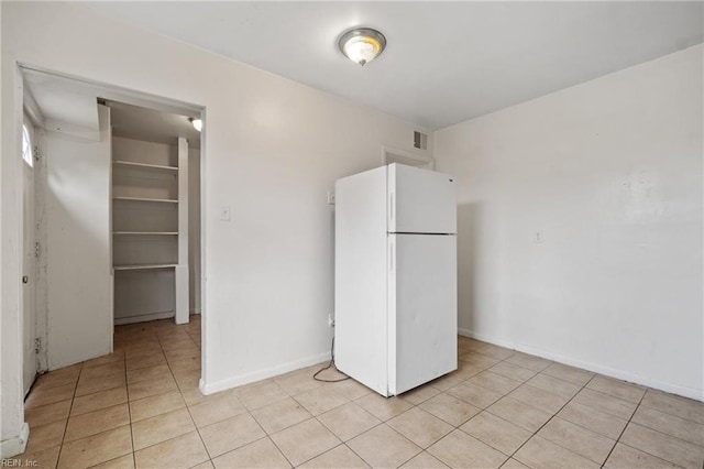 kitchen featuring light tile patterned floors, visible vents, freestanding refrigerator, and baseboards