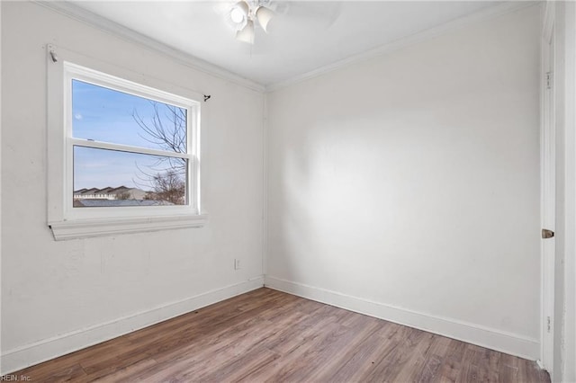 empty room with baseboards, ceiling fan, light wood finished floors, and crown molding