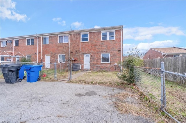 rear view of house featuring central AC, brick siding, and fence