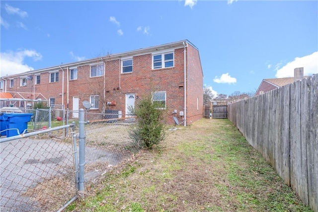 back of house featuring a fenced backyard and brick siding