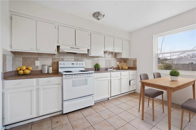 kitchen with white electric stove, dark countertops, white cabinetry, and under cabinet range hood