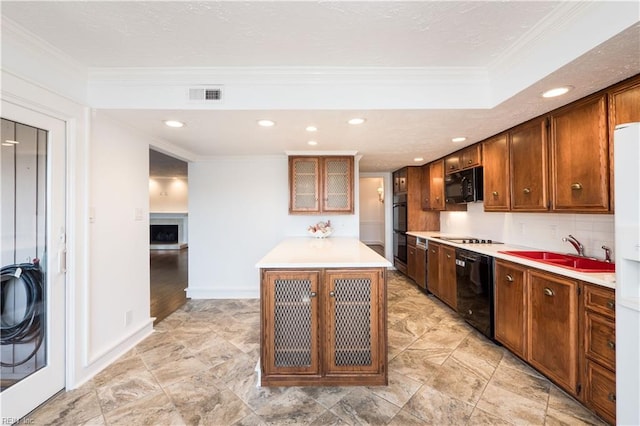 kitchen featuring glass insert cabinets, a center island, light countertops, black appliances, and a sink