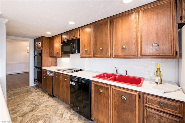 kitchen with brown cabinetry, light countertops, a sink, and black appliances