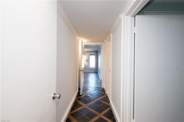 corridor with stone finish floor, baseboards, and ornamental molding