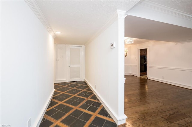 hallway featuring ornamental molding, dark wood finished floors, a textured ceiling, and baseboards