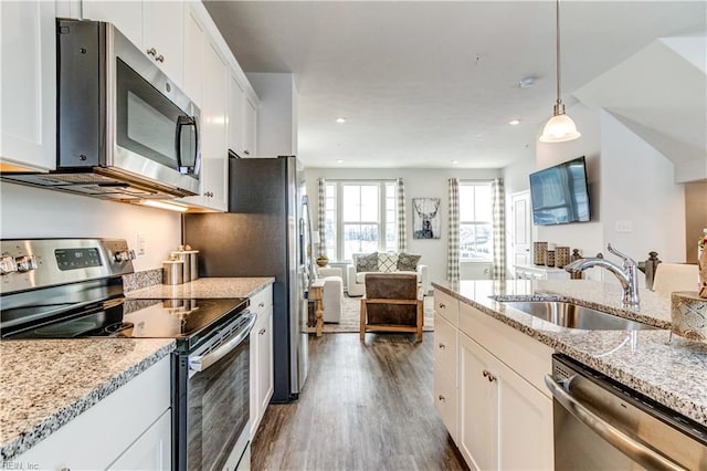 kitchen with white cabinets, stainless steel appliances, a sink, and open floor plan