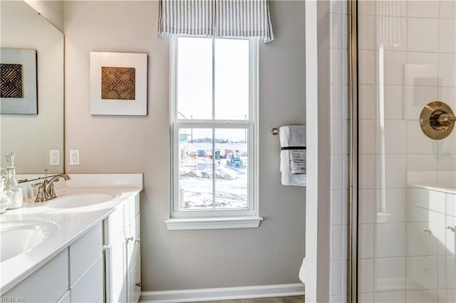 bathroom with a healthy amount of sunlight, double vanity, a tile shower, and a sink