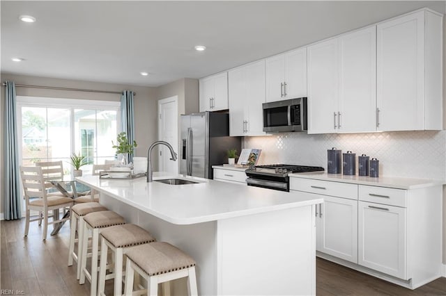 kitchen with a breakfast bar, a center island with sink, stainless steel appliances, light countertops, and a sink