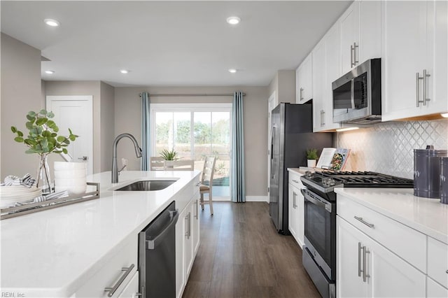 kitchen with white cabinets, decorative backsplash, appliances with stainless steel finishes, light countertops, and a sink