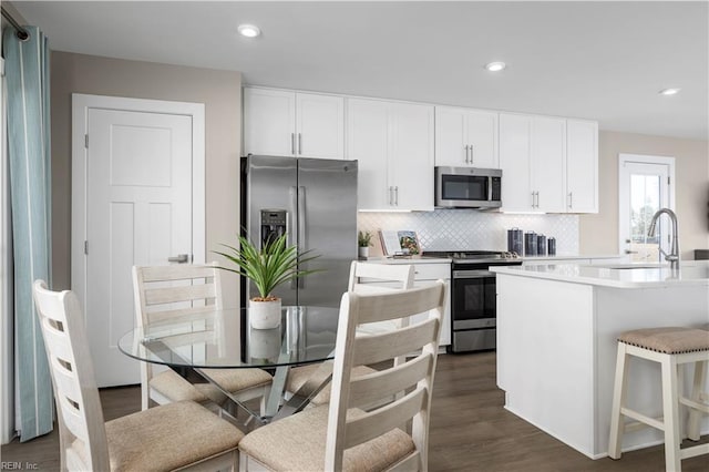 kitchen with a sink, white cabinetry, light countertops, appliances with stainless steel finishes, and backsplash