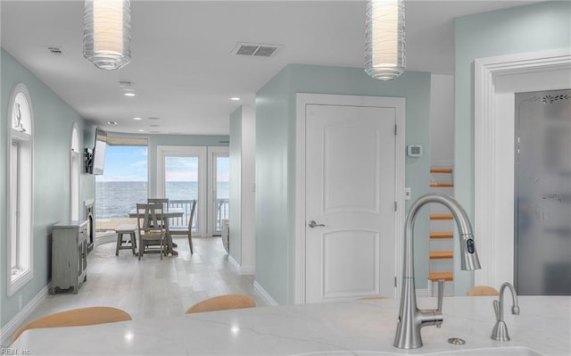 interior space featuring light stone countertops, light wood finished floors, visible vents, and a sink