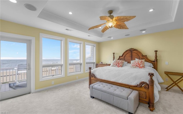 bedroom with light carpet, access to outside, a tray ceiling, and baseboards