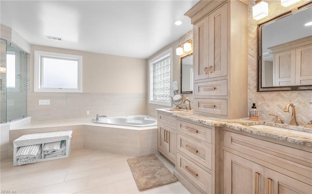 bathroom featuring a bath, a sink, visible vents, and decorative backsplash