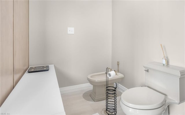 bathroom with a bidet, tile patterned floors, toilet, and baseboards