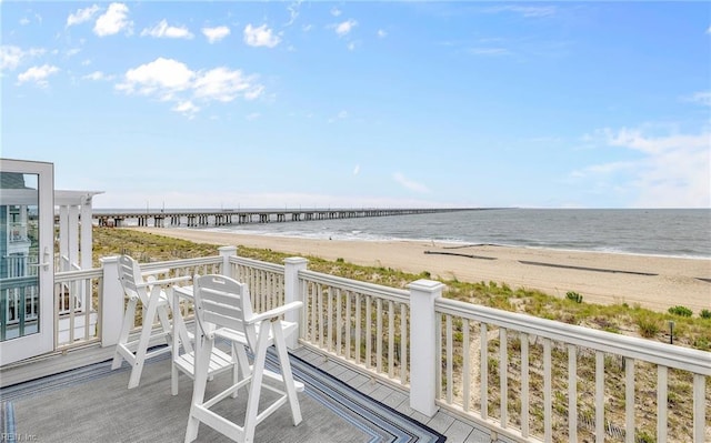 wooden terrace with a water view and a view of the beach