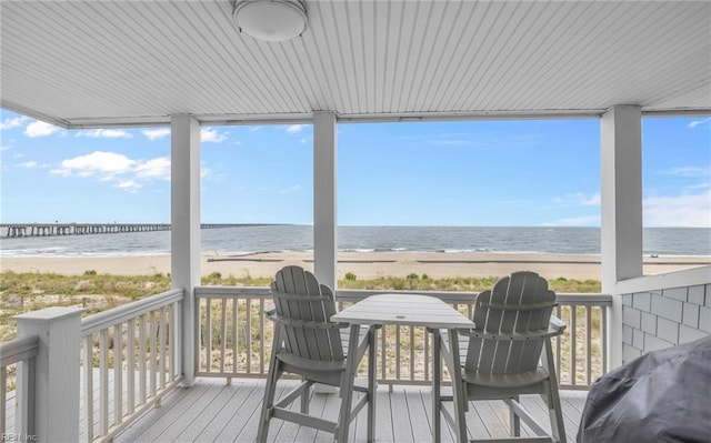 wooden terrace featuring a water view, a beach view, and grilling area