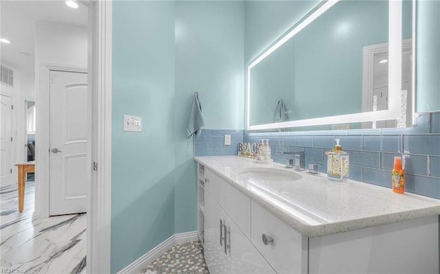 bathroom with baseboards, decorative backsplash, marble finish floor, vanity, and recessed lighting