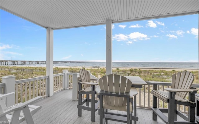 wooden deck featuring a water view and a beach view