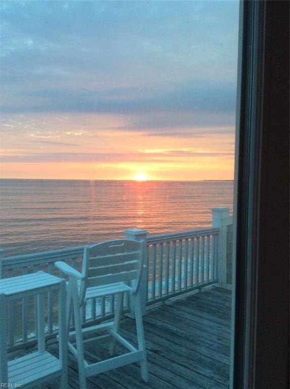 deck at dusk featuring a water view