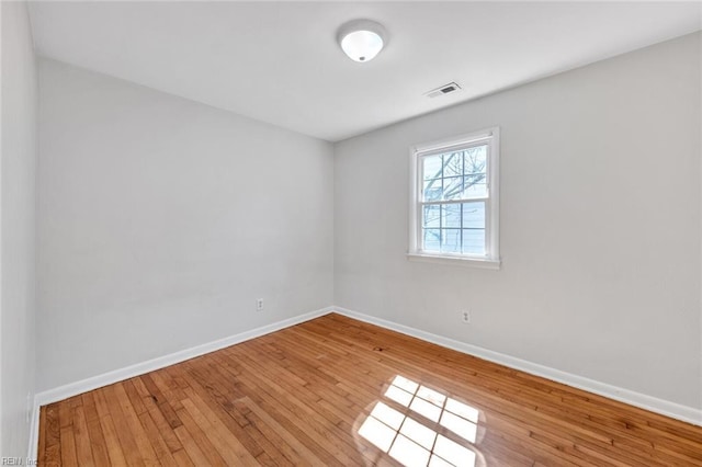 empty room with visible vents, light wood-style flooring, and baseboards