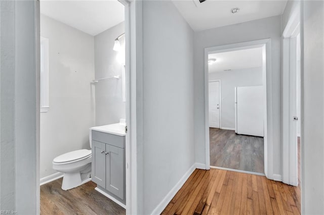 bathroom featuring toilet, wood finished floors, vanity, and baseboards