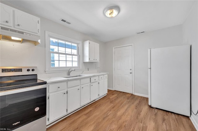 kitchen featuring under cabinet range hood, white cabinets, light countertops, stainless steel electric range, and freestanding refrigerator