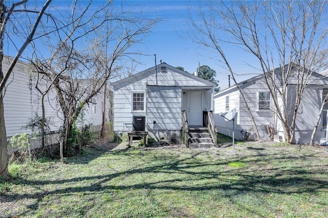 back of property with entry steps, a lawn, fence, and central air condition unit