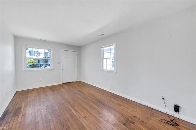 unfurnished room featuring wood finished floors, visible vents, and baseboards