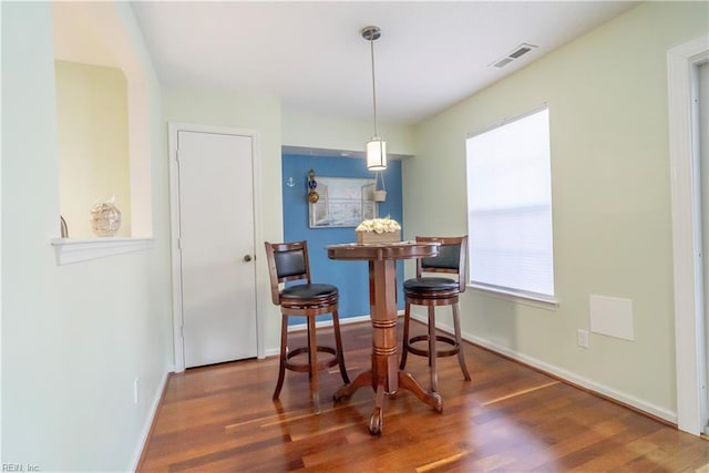 dining space with dark wood-style floors, visible vents, and baseboards