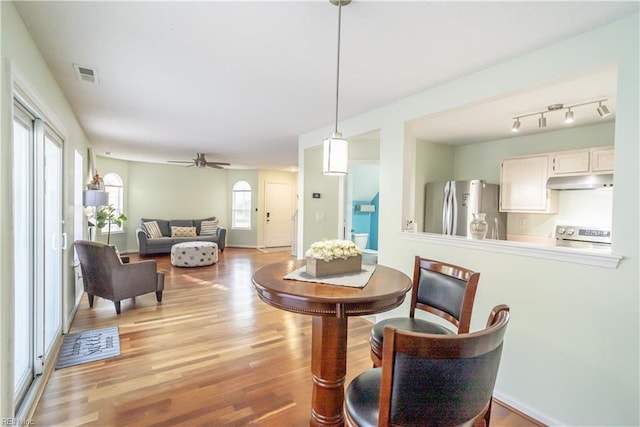 dining area with light wood finished floors, ceiling fan, visible vents, and baseboards