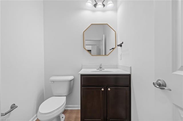 bathroom featuring baseboards, vanity, toilet, and wood finished floors