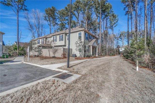 exterior space featuring central AC unit, a residential view, fence, and aphalt driveway