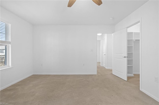 unfurnished bedroom with light carpet, a spacious closet, and baseboards