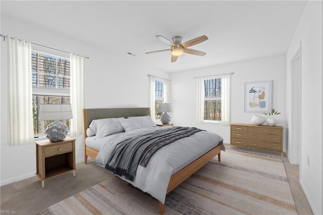 bedroom with light carpet, ceiling fan, visible vents, and baseboards