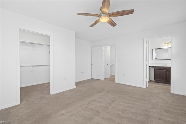 unfurnished bedroom featuring connected bathroom, light colored carpet, baseboards, a spacious closet, and a closet