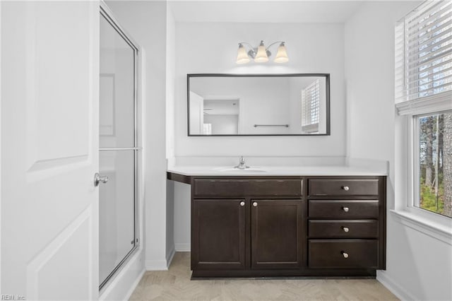 full bath with vanity, baseboards, and an enclosed shower