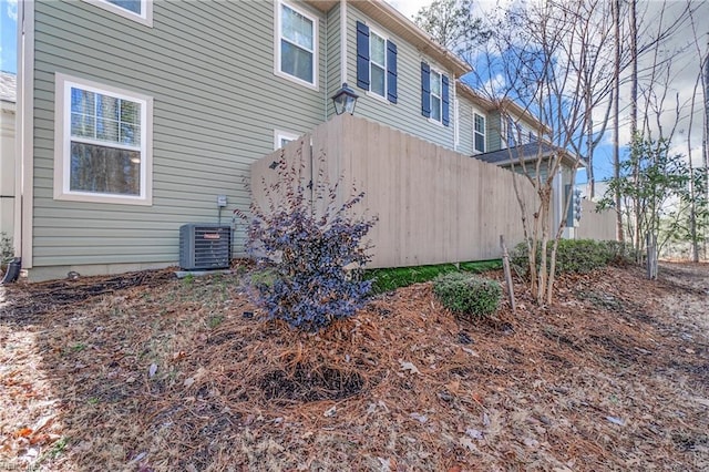 view of side of property with central AC and fence