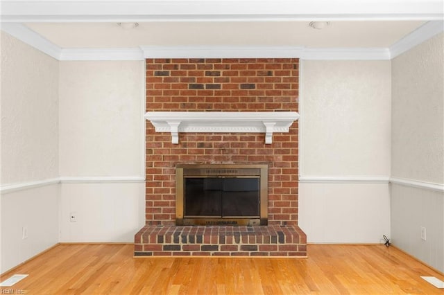 interior details featuring ornamental molding, a fireplace, and wood finished floors