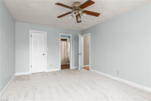 unfurnished bedroom featuring light carpet, ensuite bath, a ceiling fan, and baseboards