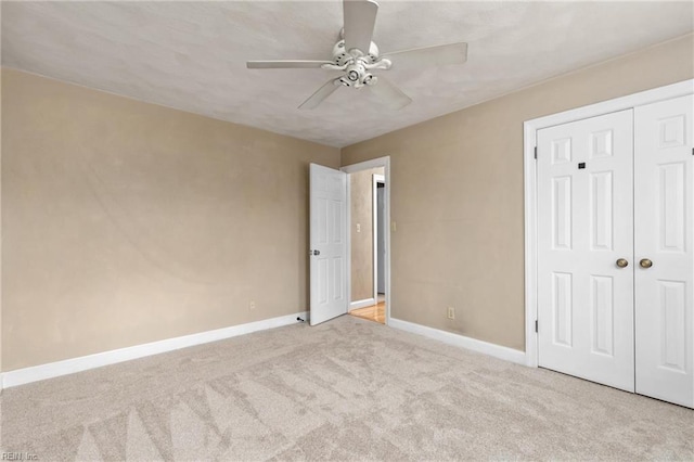 unfurnished bedroom featuring light carpet, a closet, a ceiling fan, and baseboards