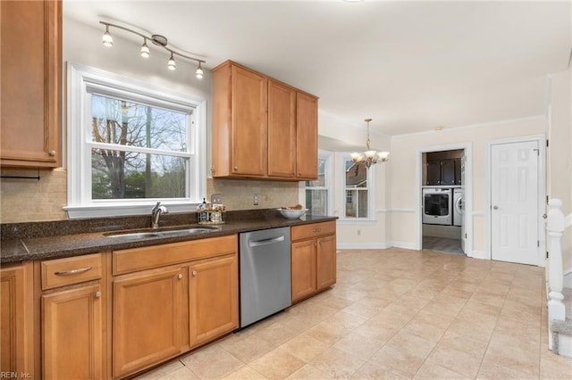 kitchen with washing machine and dryer, a sink, stainless steel dishwasher, backsplash, and dark countertops