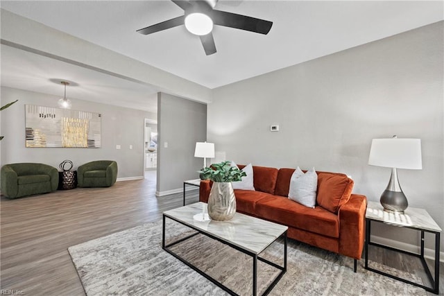 living area with a ceiling fan, baseboards, and wood finished floors