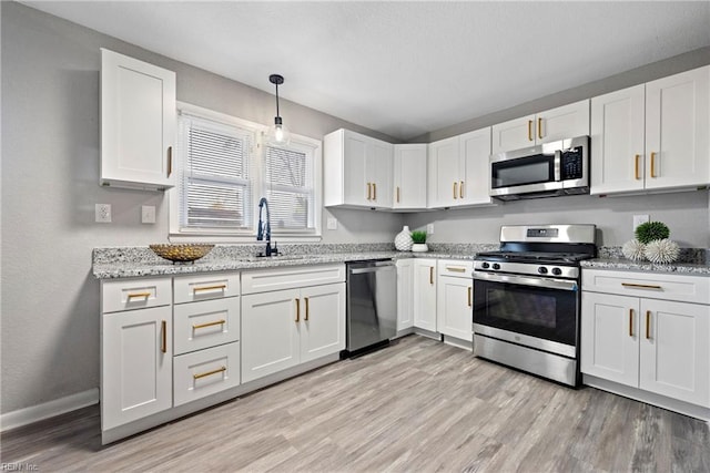 kitchen with baseboards, appliances with stainless steel finishes, light wood-style floors, white cabinetry, and a sink