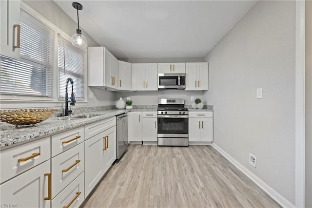 kitchen with appliances with stainless steel finishes, white cabinetry, a sink, and light wood finished floors