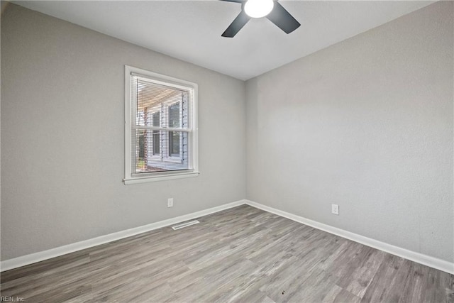 unfurnished room with visible vents, baseboards, ceiling fan, and wood finished floors