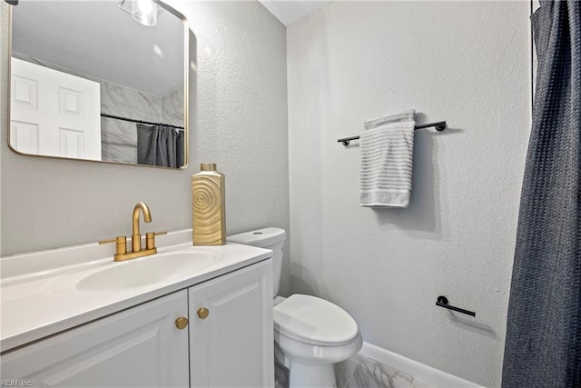 bathroom featuring a textured wall, vanity, and toilet