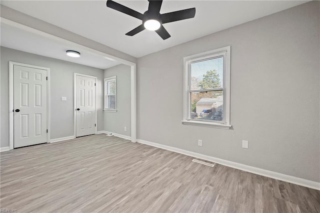 empty room featuring baseboards, ceiling fan, visible vents, and light wood-style floors